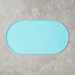 Light blue bath mat on a beige tiled floor