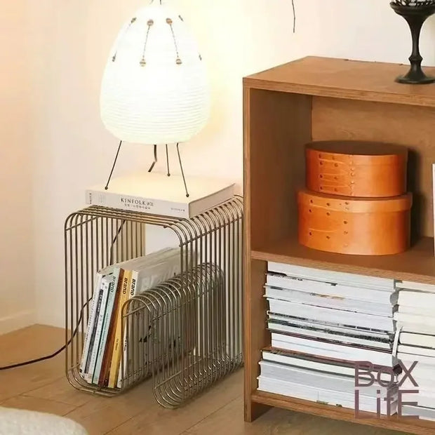 Wooden shelf with books and decorative boxes next to a wire magazine holder.