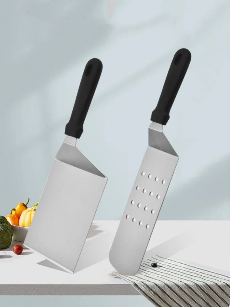 Two metal graters with black handles on a light surface with fruits in the background.