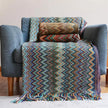 Colorful zigzag patterned blanket draped over a blue armchair.