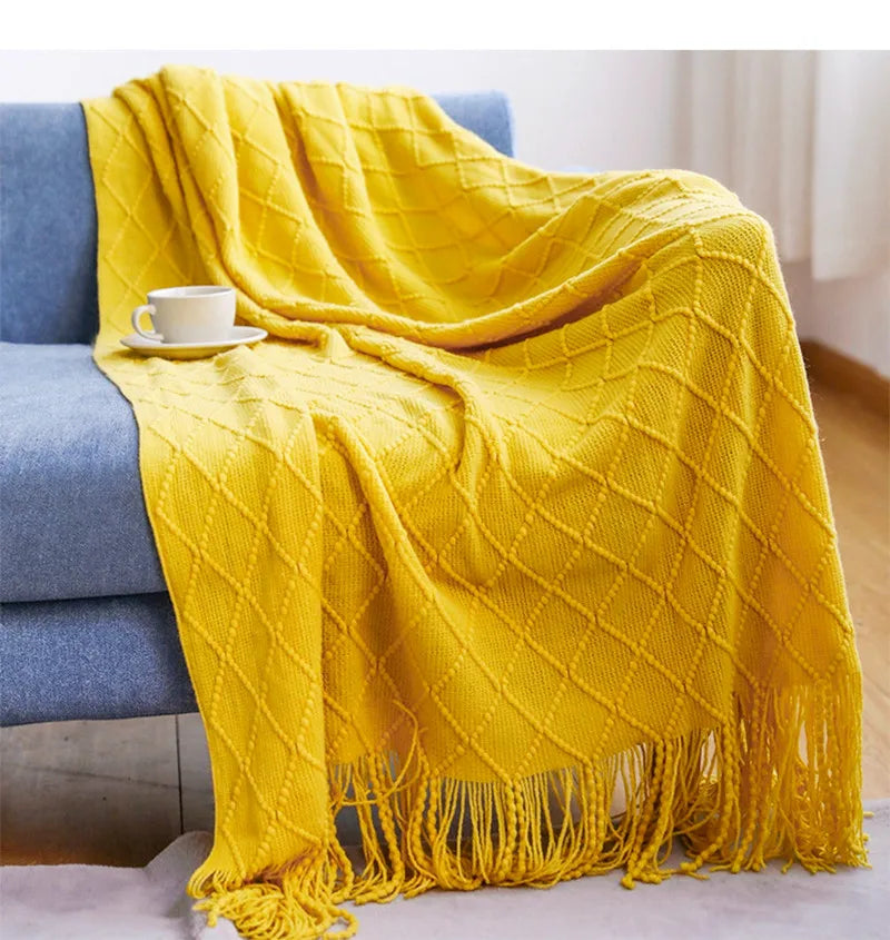 Yellow blanket draped over a blue sofa with a cup on a small table.