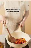 Person wearing an apron with text 'Wear-resistant and durable' cooking with a wooden spoon.