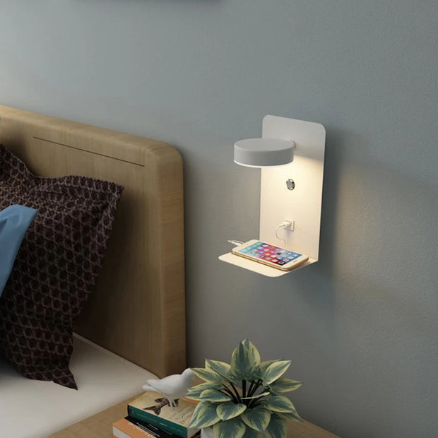 Wall-mounted night light with phone charging station in a bedroom setting.
