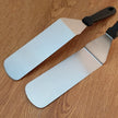 Two spatulas with light blue silicone heads on a wooden surface