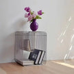 Wire side table with books and a vase of flowers on a light wooden floor.