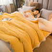 Woman lying on a bed with a yellow comforter in a cozy bedroom.
