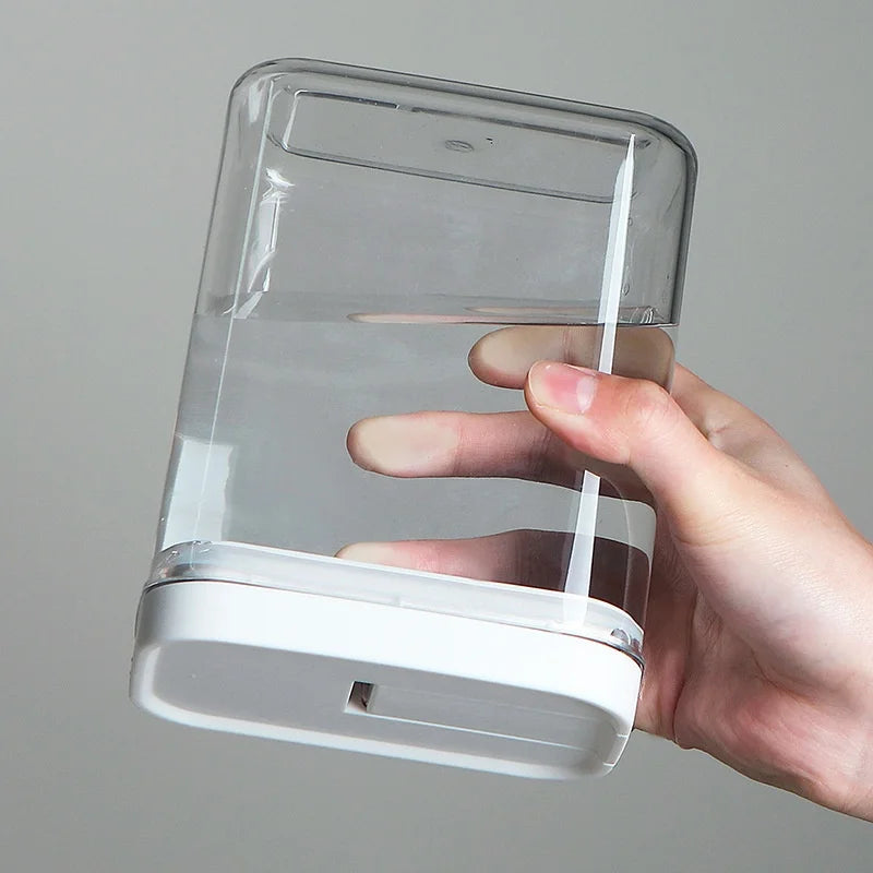 Hand holding a clear plastic container with a white base against a gray background
