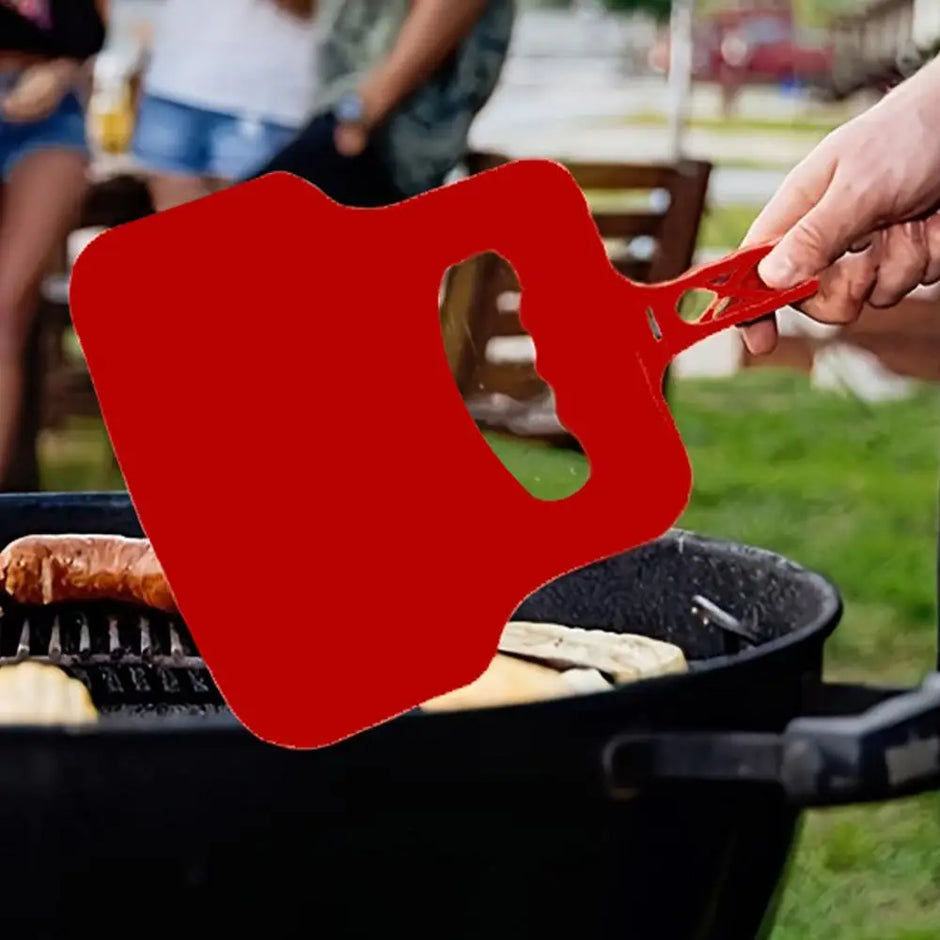 Red guitar-shaped spatula being used on a grill outdoors