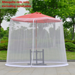 Mosquito netting around a red outdoor umbrella with greenery in the background