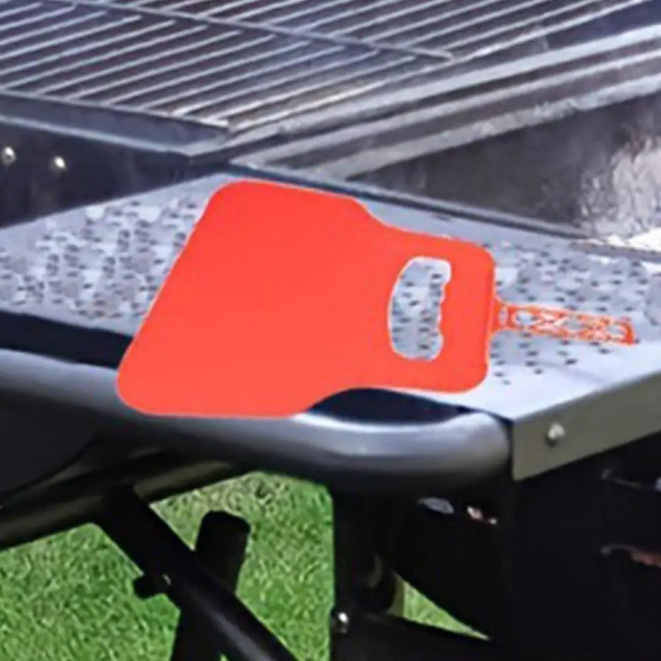 Red grill cleaning brush on a grill with visible brand name