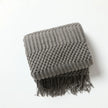 Gray textured blanket with fringes on a white background