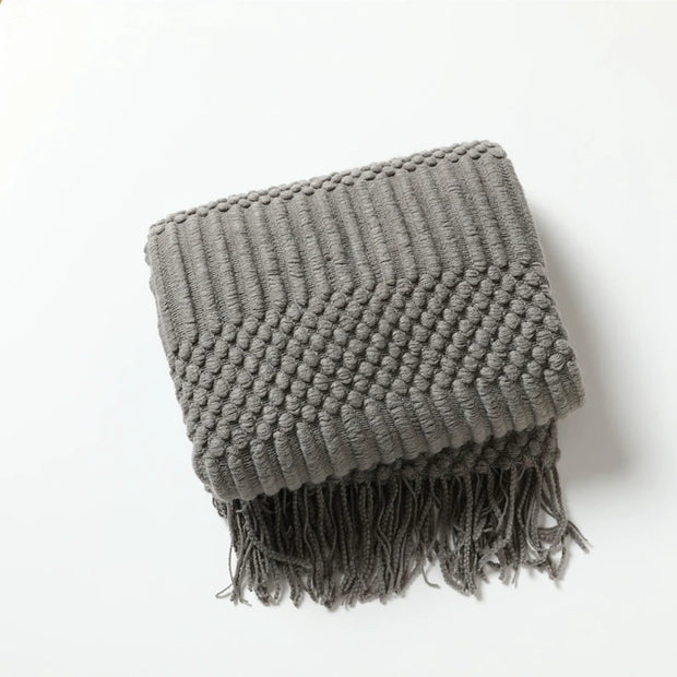 Gray textured blanket with fringes on a white background