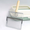 Metal scoop with wooden handle in front of a white litter box on a light gray background