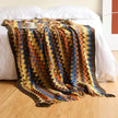 Colorful zigzag patterned blanket draped over a bed in a bedroom setting.