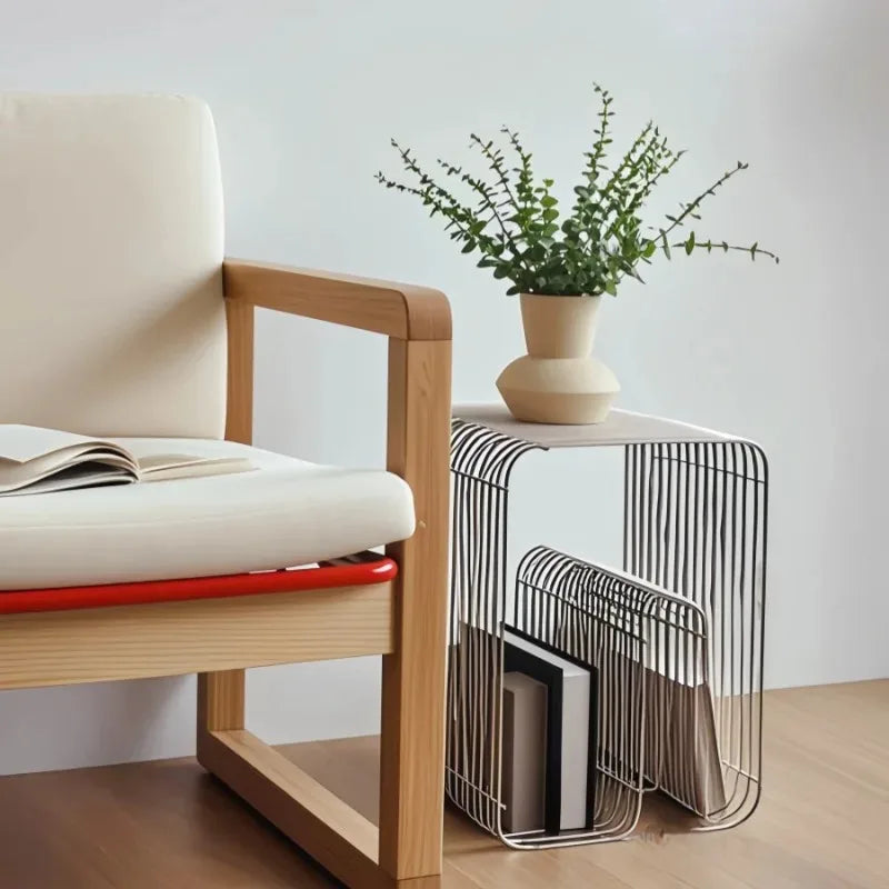 Modern chair with a magazine and a small table with a plant and books against a light background
