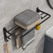 Black metal towel rack with folded towels on a bathroom wall.