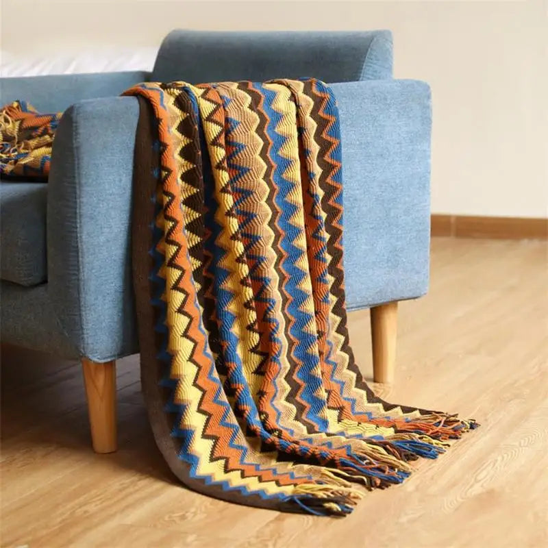 Colorful patterned blanket draped over a blue armchair on a wooden floor.