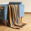 Colorful patterned blanket draped over a blue armchair on a wooden floor.