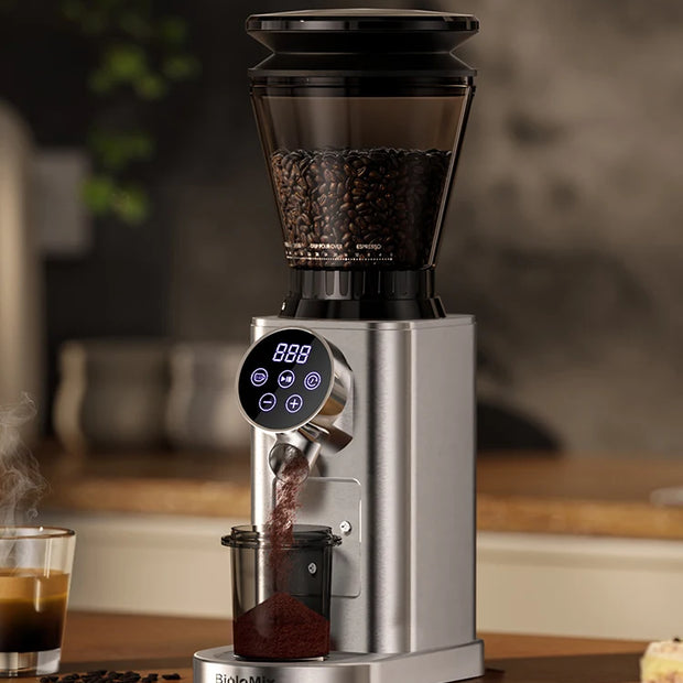 Coffee grinder with digital display on a wooden surface, surrounded by coffee beans and a glass of coffee.