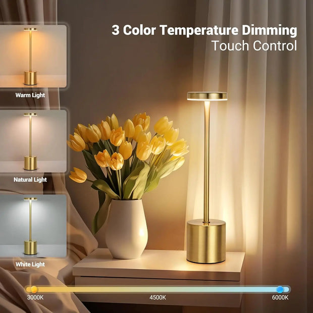 Gold table lamp with 3 color temperature settings on a nightstand with flowers.