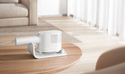 White electronic device on a wooden table in a bright room with light-colored furniture.