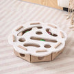 Cat toy with cardboard base and white top on a striped carpet