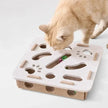 Cat playing with a cardboard puzzle toy on a light background