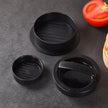 Black plastic burger press on a gray surface with a tomato and bun in the background