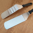 Two spatulas with different designs on a wooden surface