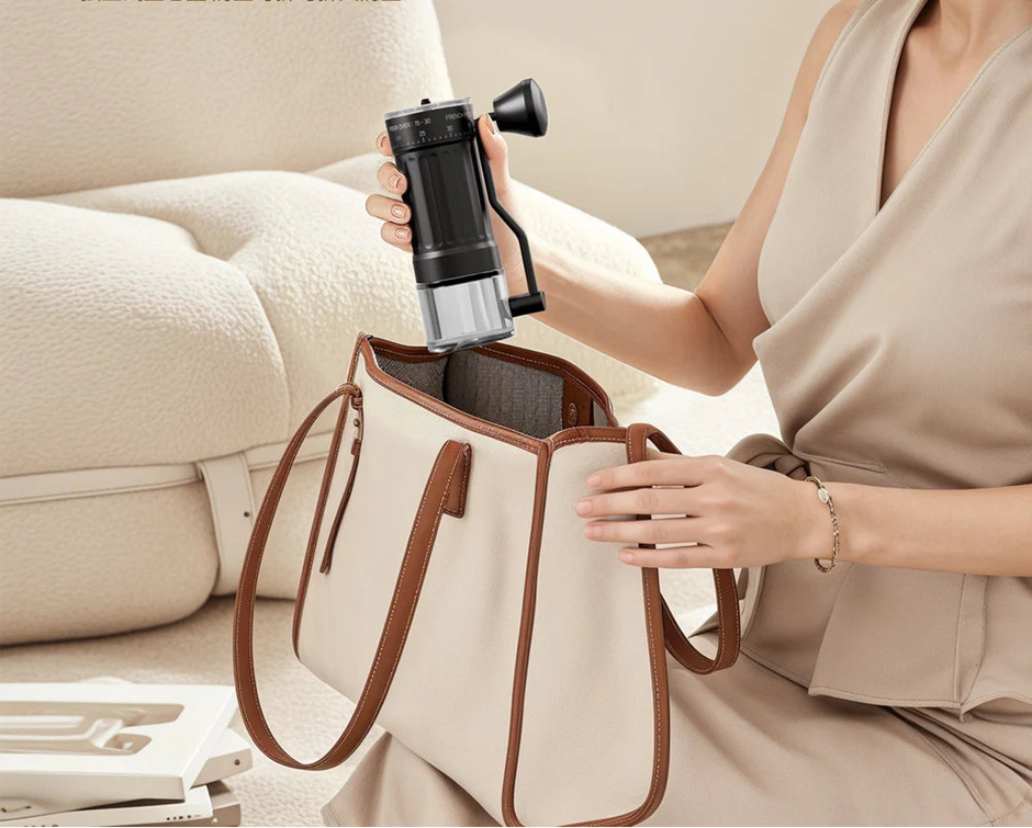 Woman placing a portable coffee maker into a beige handbag in a living room setting.