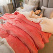 Woman lying in bed under a pink blanket with a cozy bedroom setting.