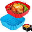 Silicone baking pans in red and blue with a roasted chicken and fries on a white background