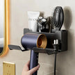 Wall-mounted hair dryer holder with various grooming tools on a bathroom wall.