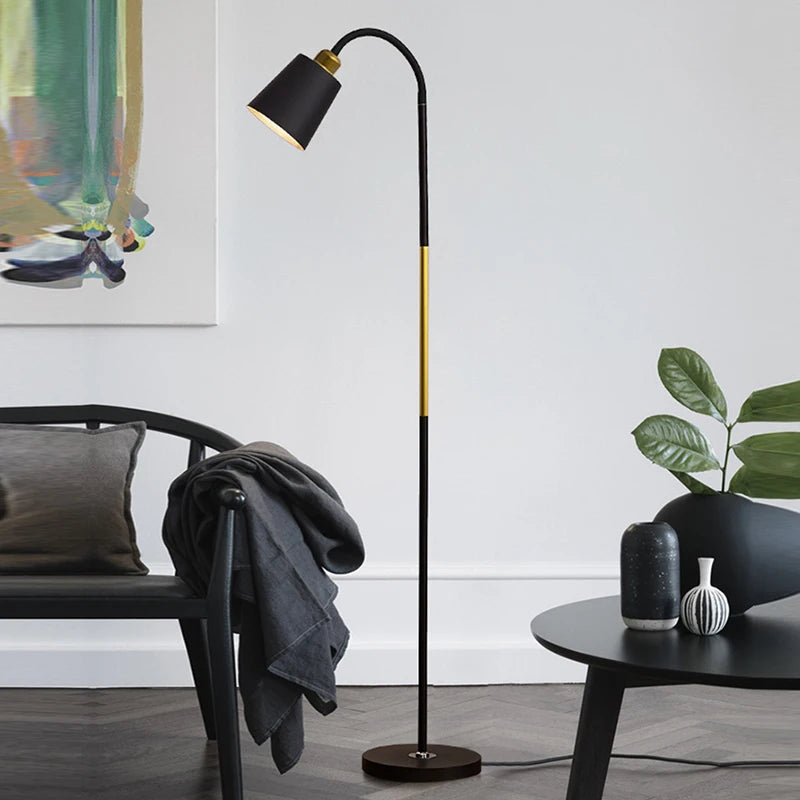 Modern black floor lamp in a living room setting with a chair and table.