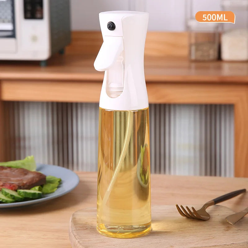 Spray bottle with oil on a table with a plate of salad and cutlery in the background