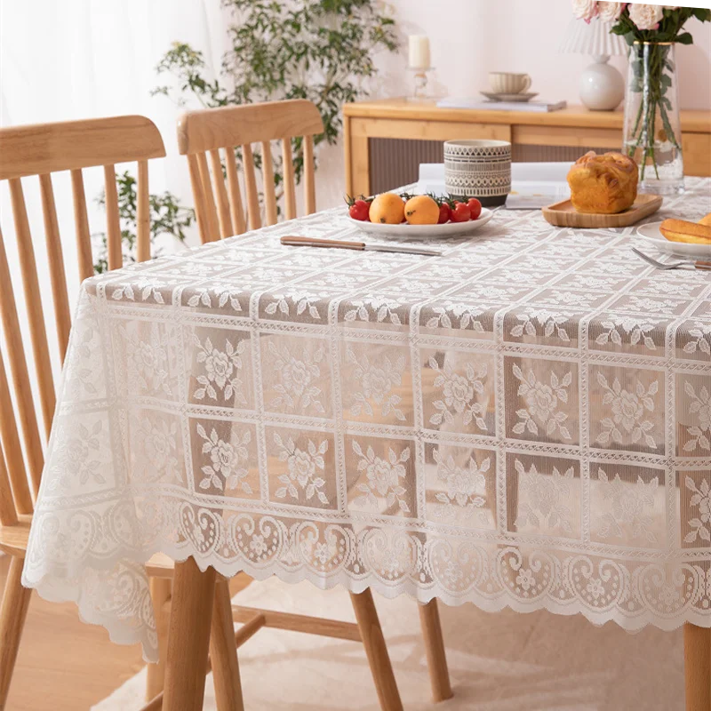 Dining table with lace tablecloth, fruit plate, and muffins in a bright room.