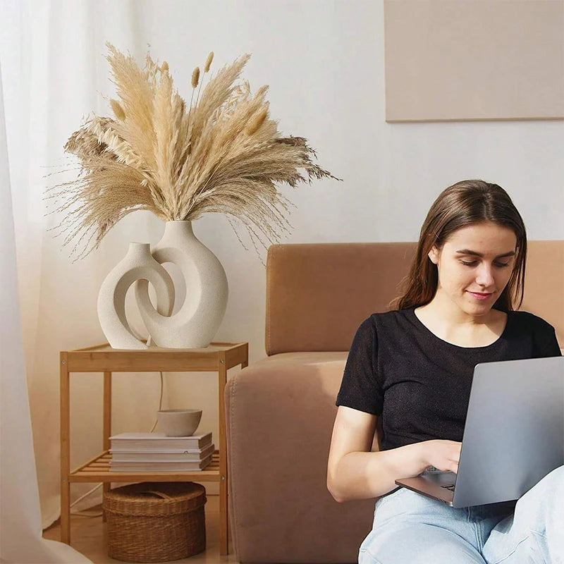 Woman using a laptop on a couch with decorative elements in the background