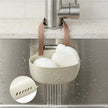 Kitchen sponge holder with sponges hanging under a faucet in a kitchen setting.