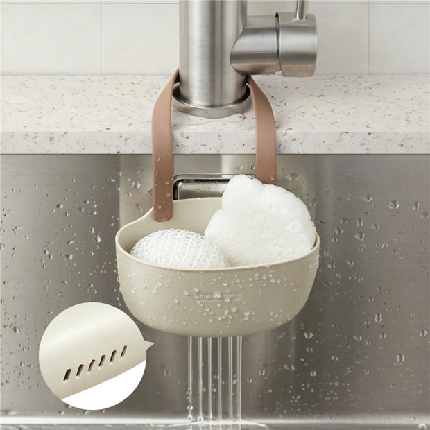 Kitchen sponge holder with sponges hanging under a faucet in a kitchen setting.