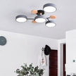 Modern ceiling light fixture in a room with a clock, plant, and coat rack.
