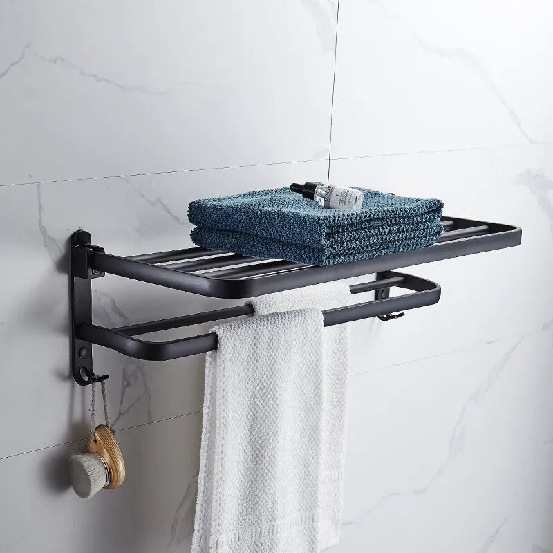 Black towel rack with folded towels and a brush on a tiled bathroom wall.