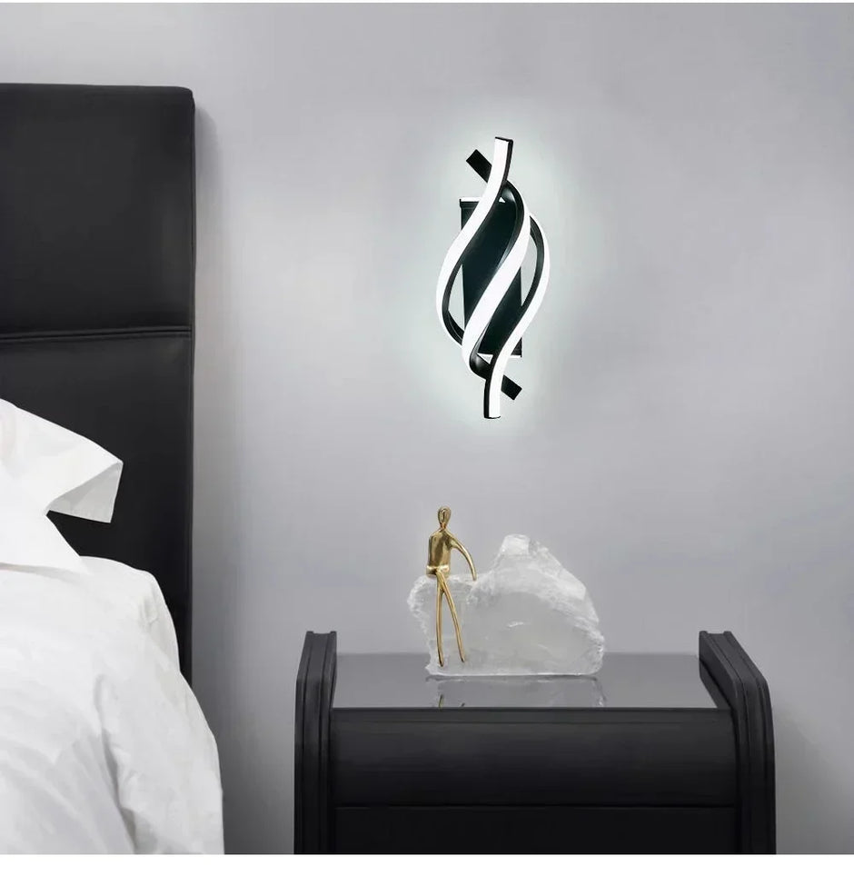 Modern wall light fixture on a gray wall above a nightstand with decorative items.