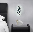 Modern wall light fixture on a gray wall above a nightstand with decorative items.