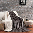 Gray and white blanket draped over a sofa against a brick wall.