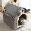 Dog lying inside a gray pet house with a fluffy interior, on a light-colored rug.