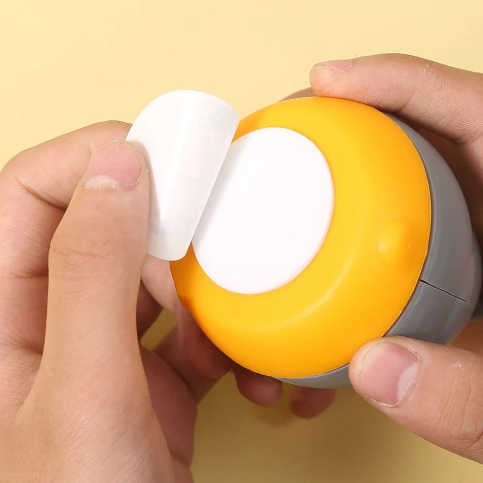 Hand holding a small orange device with a white component against a yellow background