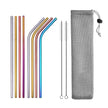 Set of colorful metal straws with cleaning brush and mesh pouch on a white background