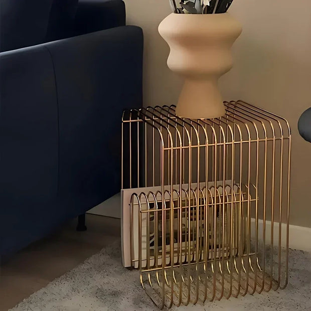 Gold wire magazine rack on a carpeted floor with a vase in the background