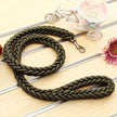 Green braided dog leash on a wooden surface with decorative elements.