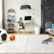 Children's room with desk, toys, and sports balls on a white rug.